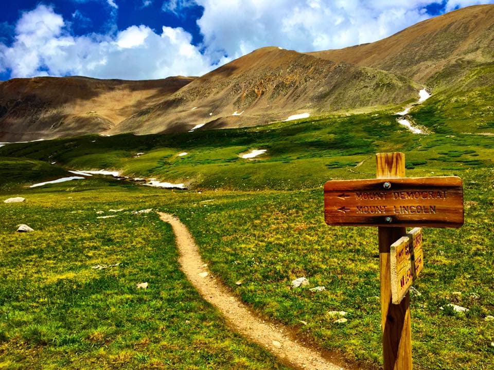 a trail post with a hiking trail stretching into the distance