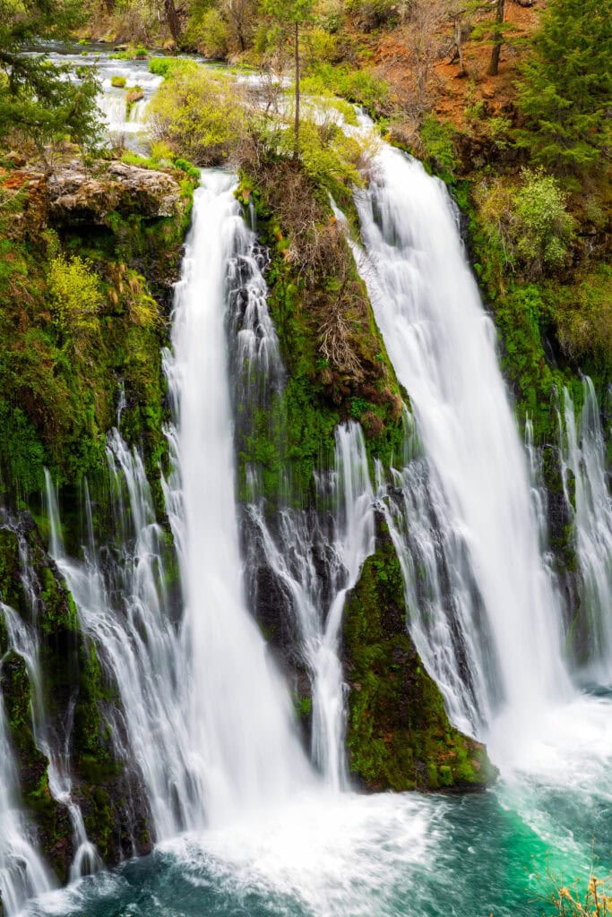 Side-angle view of Burney Falls with lush green moss covering the surrounding rock walls at McArthur-Burney Falls Memorial State Park, California