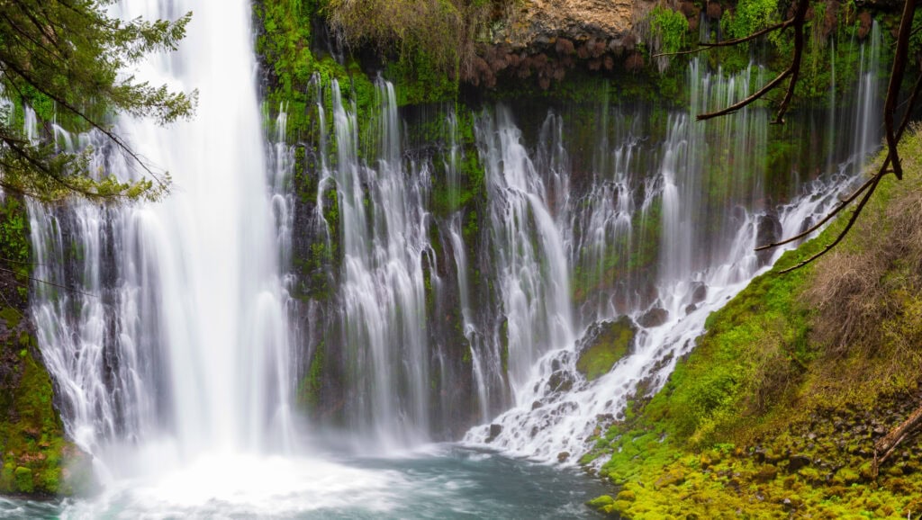 Burney Falls framed tightly with the main plunge and secondary cascades visible against dark rock at McArthur-Burney Falls Memorial State Park, California