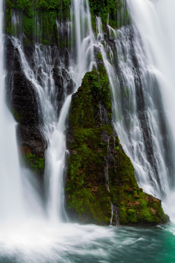 Burney Falls with multiple water curtains descending over dark basalt rock at McArthur-Burney Falls Memorial State Park, California