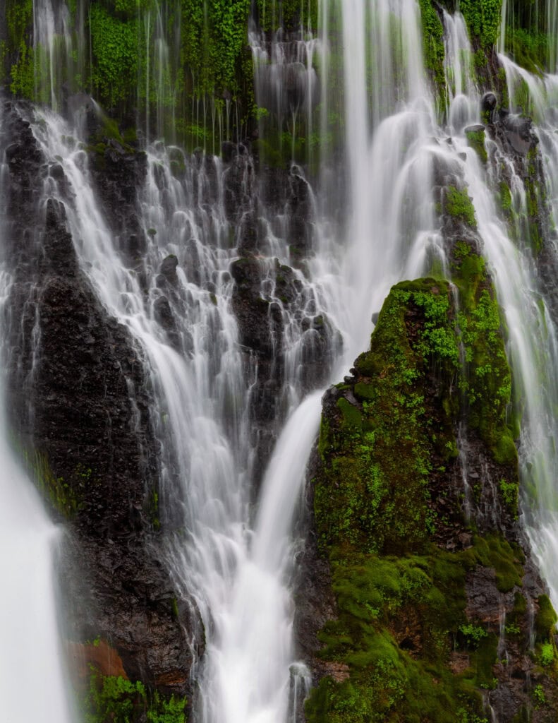 Burney Falls with multiple water curtains descending over dark basalt rock at McArthur-Burney Falls Memorial State Park, California