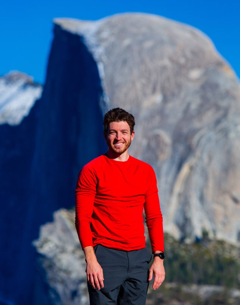 the author smiling at the camera with half dome behind him