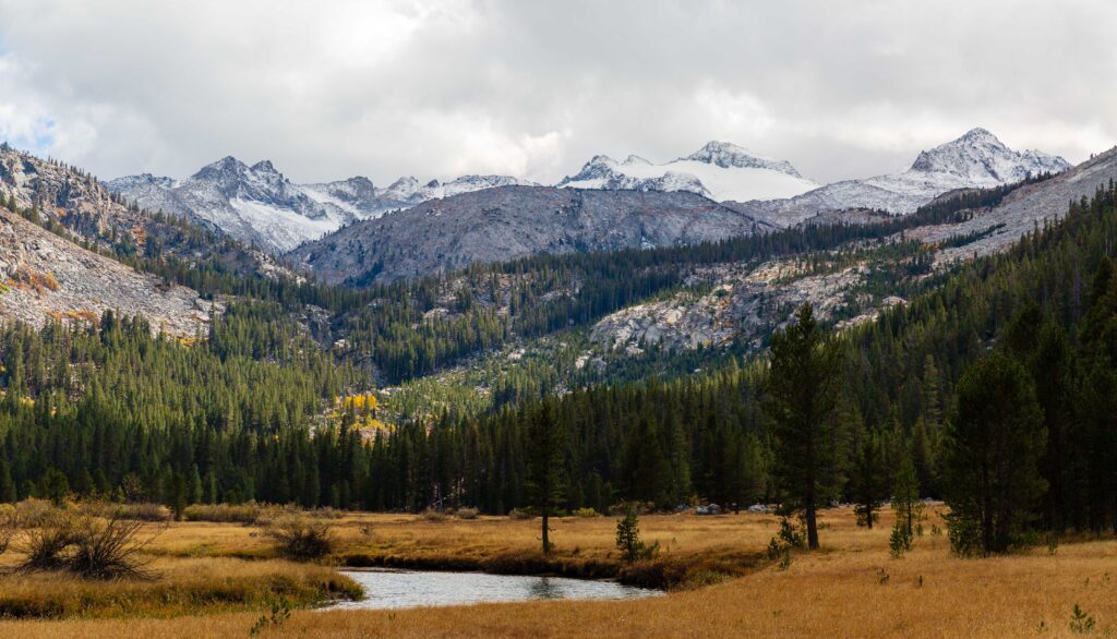 snowy mountains with a river running through the foreground