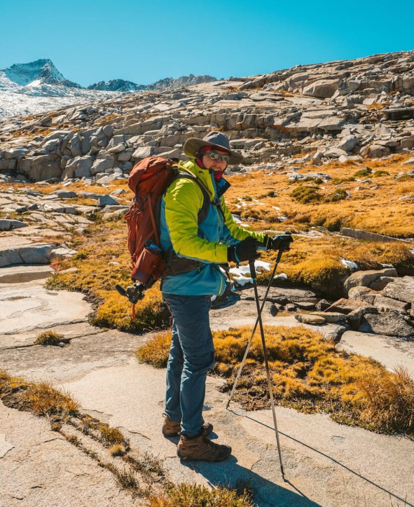 a hiker bunlded in clothes looks at the camera while hiking in yosemite national park