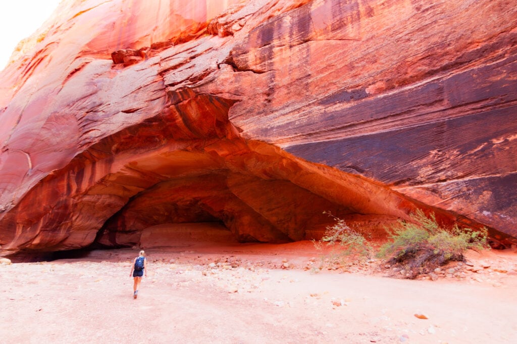 A hiker walks towards a rock arch near buckskin gulch.