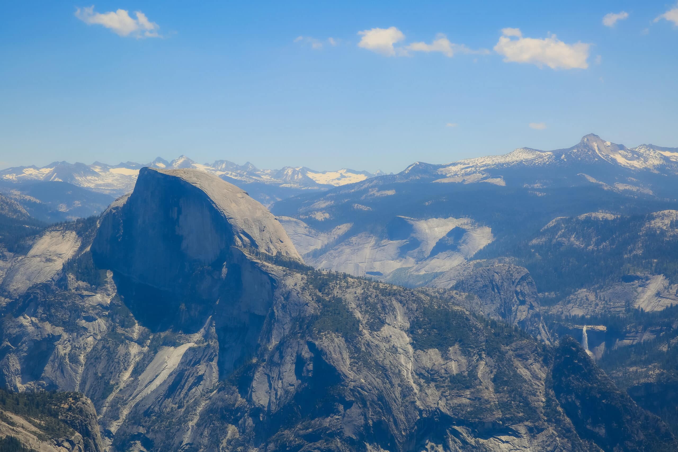 Half dome with blue sky above it. waterfalls are visible to the right.