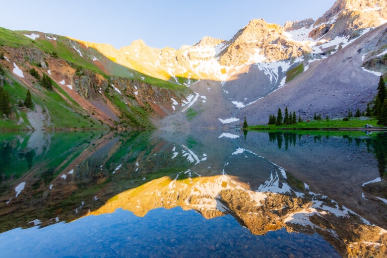 a reflection in blue lake of a snow mountain peak
