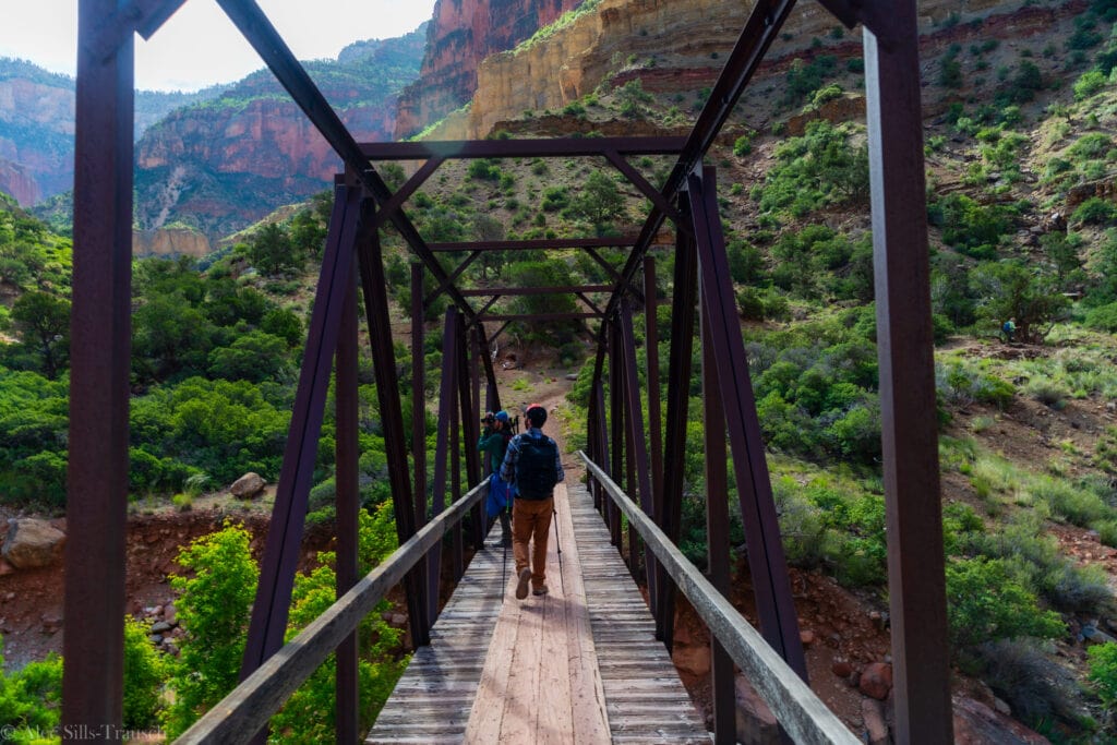 two hikers stand on a bridge on the north kaibab trail in the grand canyon