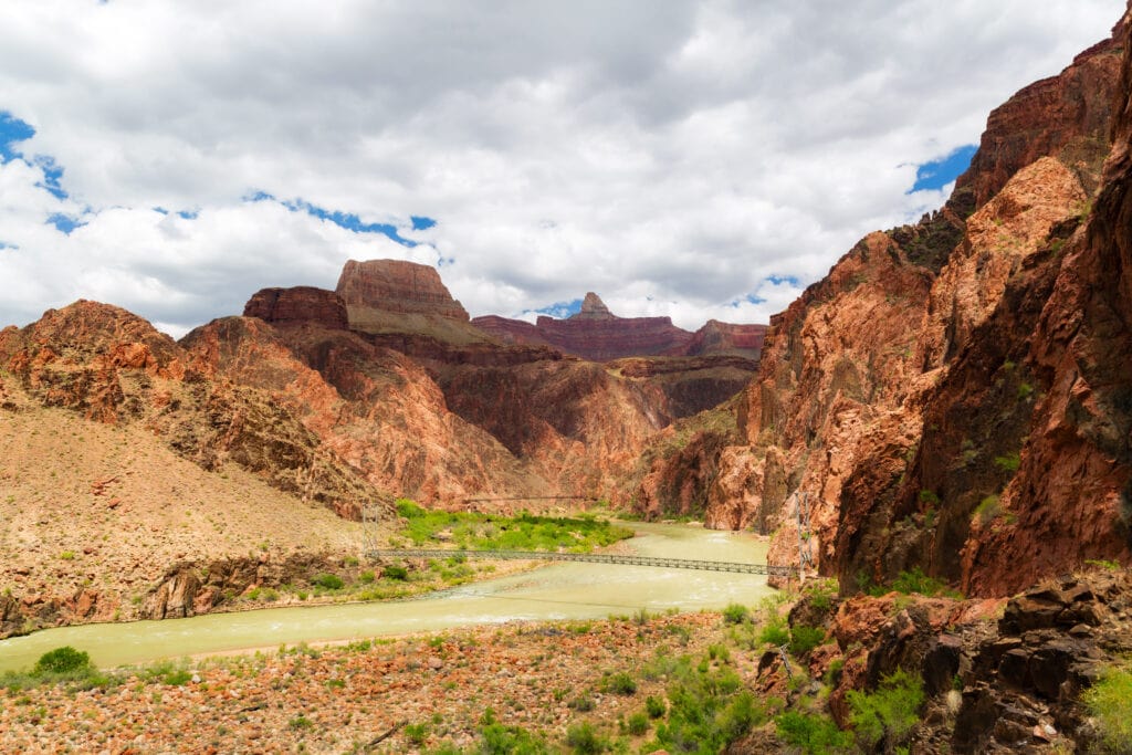 The colorado river cuts through the rock with the silver and black bridges visible.