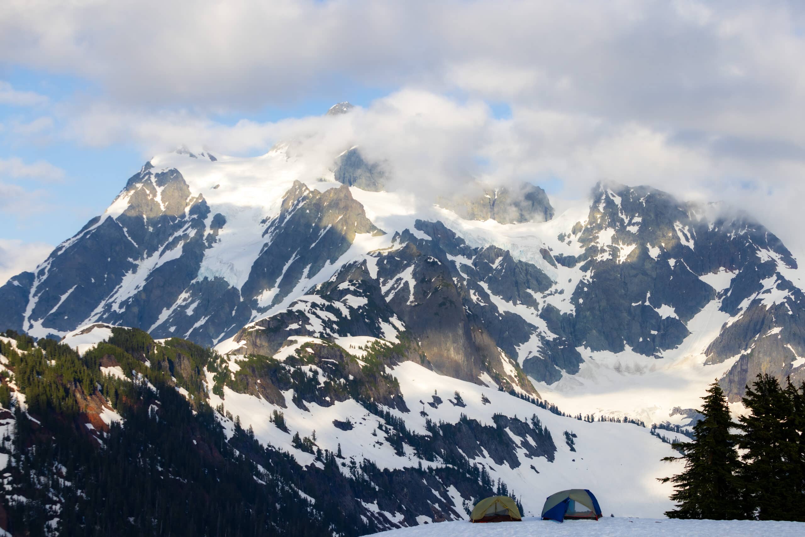 a snow covered mountains with snow clouds