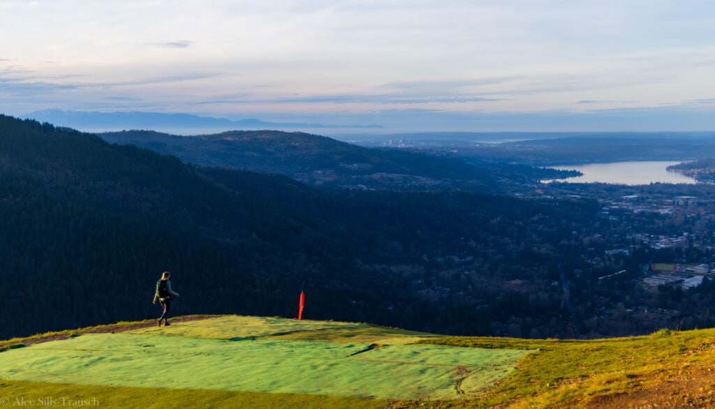 a single hiker walking out onto the north launch area at poo poo point