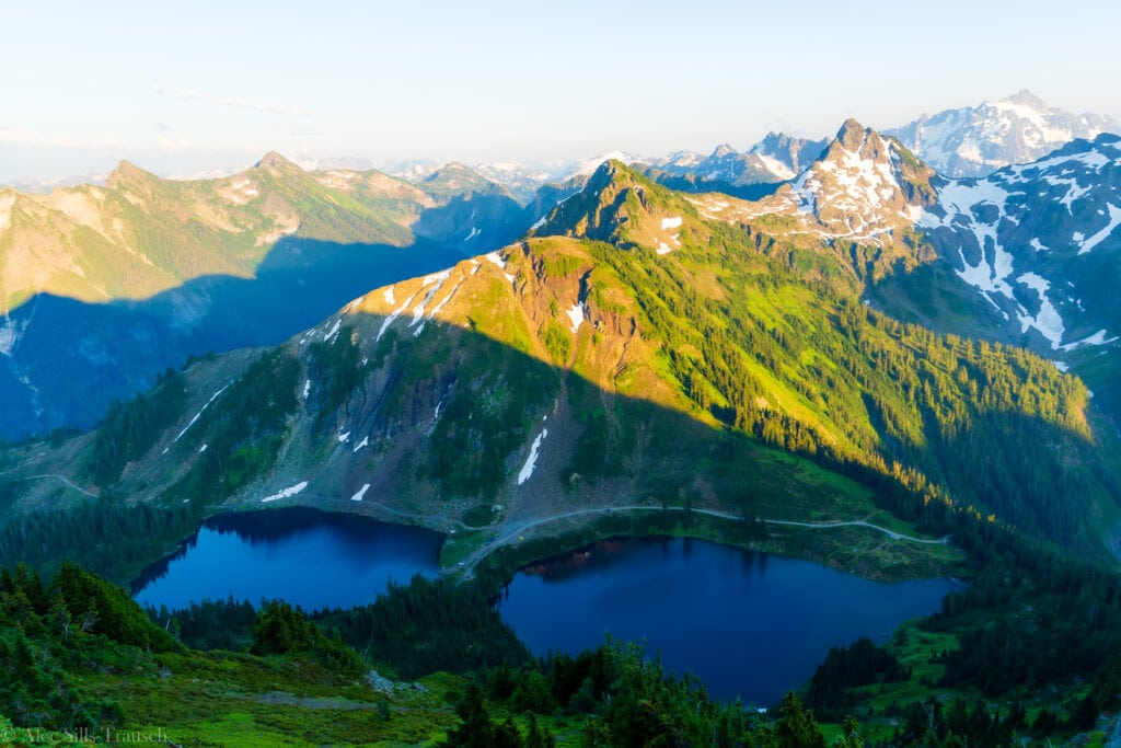 two lakes are with mountains peaks surrounding them