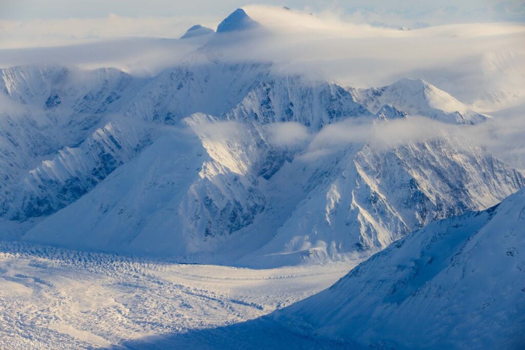 wispy clouds with a jagged snowy peak running through it