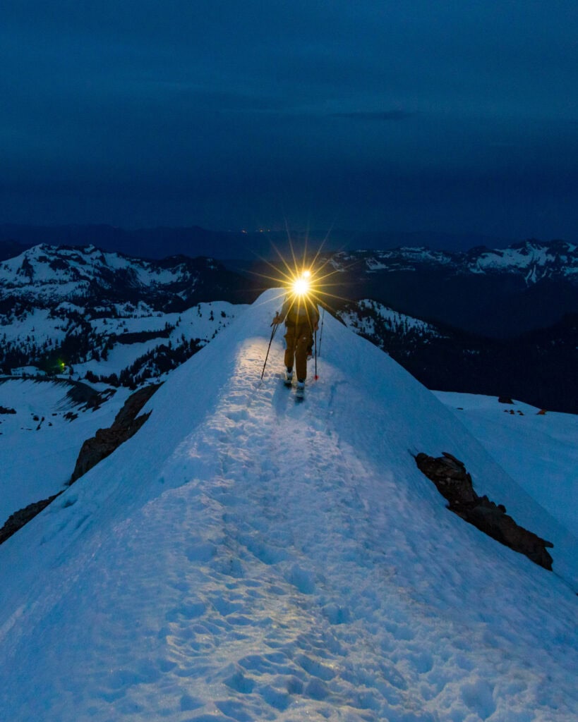 a climbers headlight flares as they walk uphill