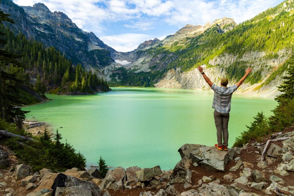 a hiker holds up his hands in front of blanca lake