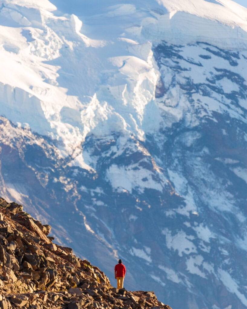 a hiker on the burroughs mountain trail looking at mount rainier