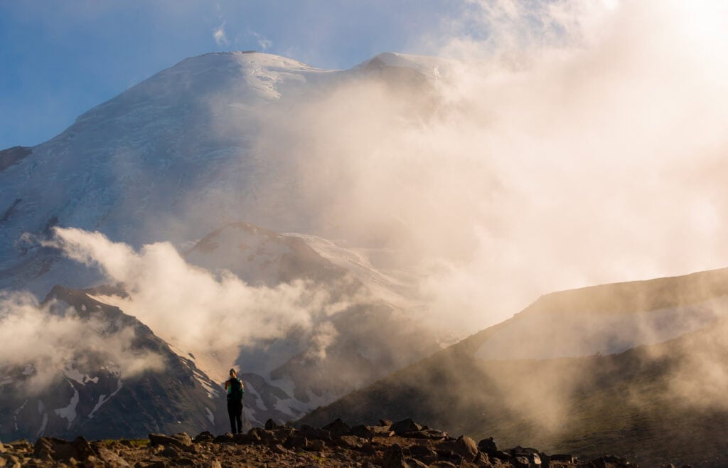 a woman looks out at mt rianier with clouds around her