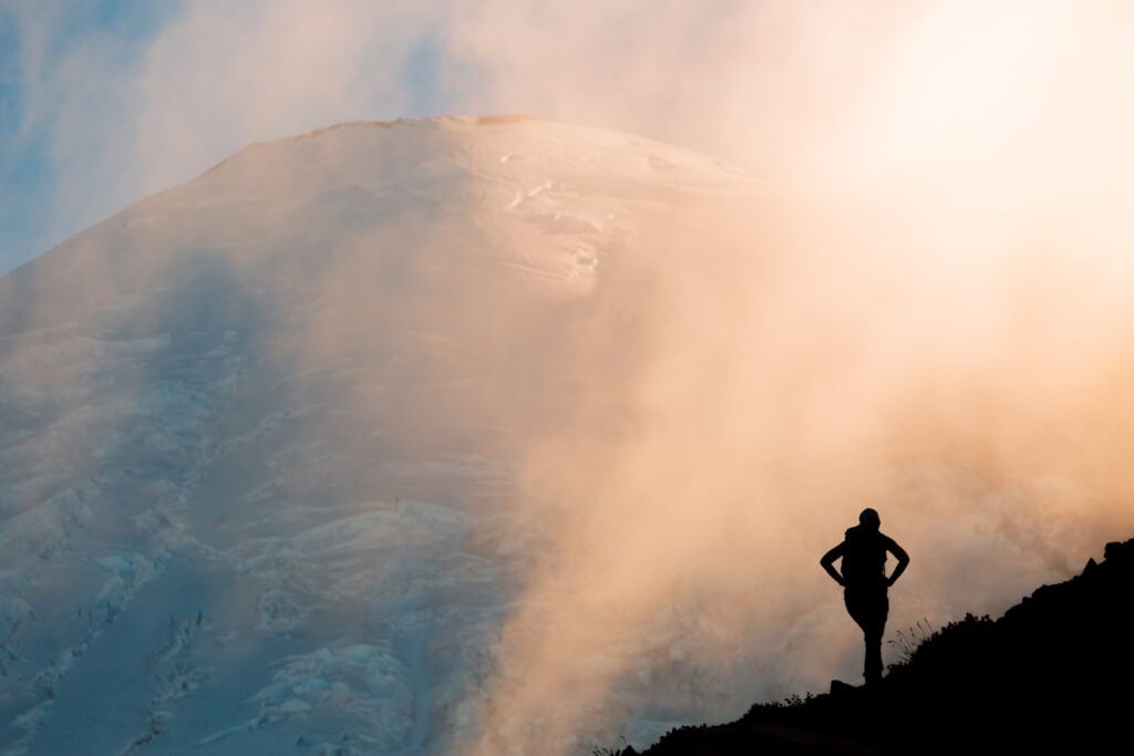a silhouette of a woman hiking on a trail 