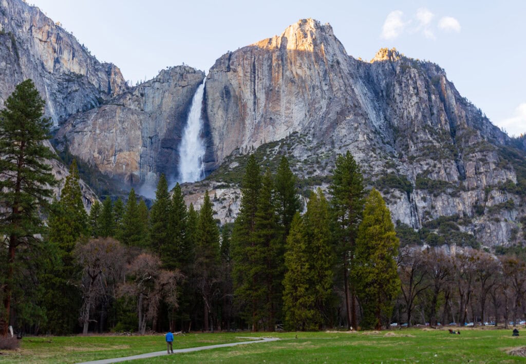 a visitor walks below yosemite falls in california