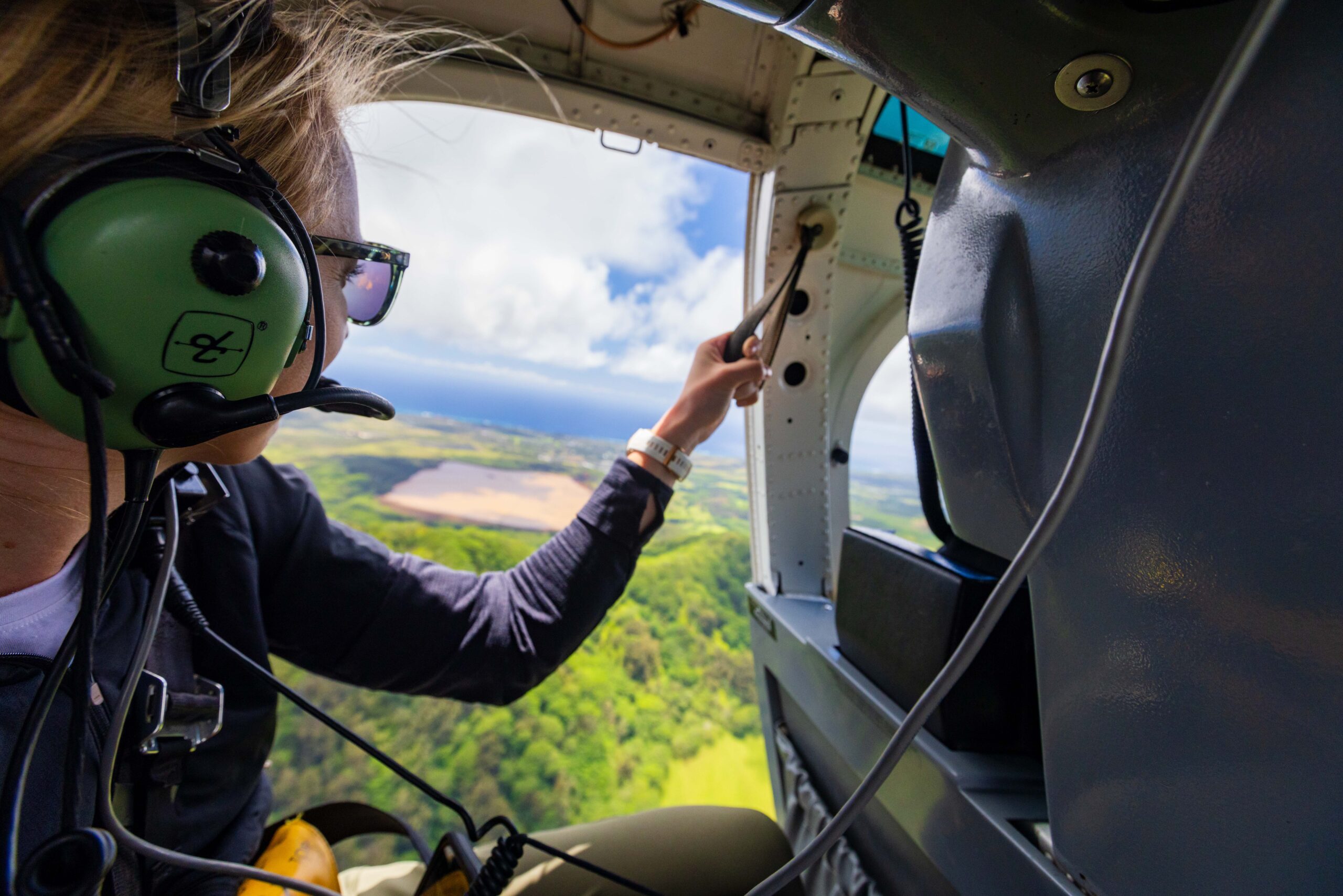 a woman looks out the door on a helicopter flight