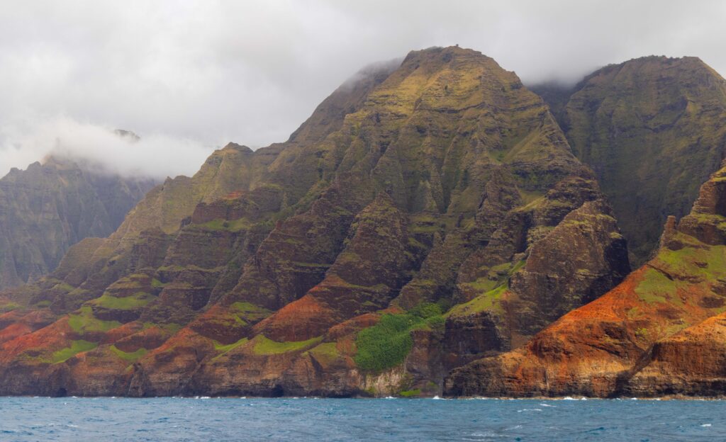 viewing the kauai coast from a na pali coast boat tour. the landscapes are green and orange