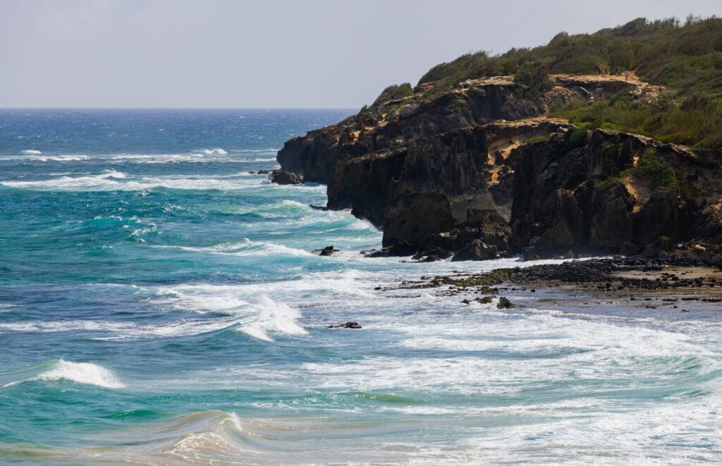 rocky kauai coast line with waves head to the shore 