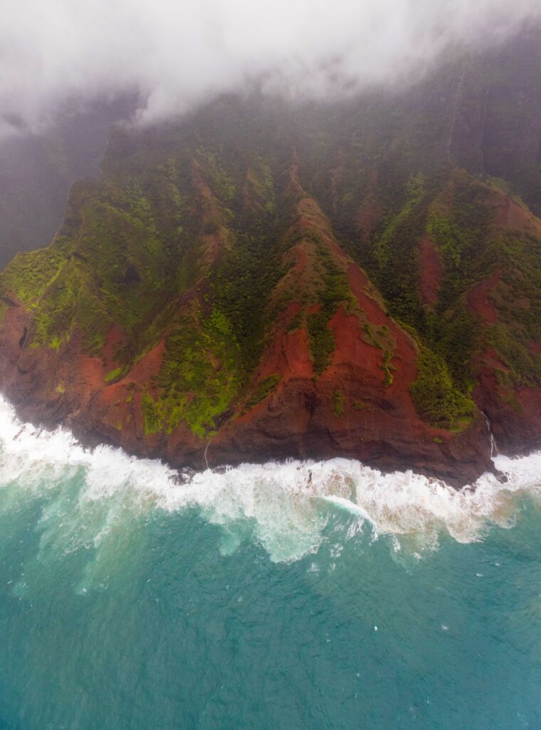 the coastline of kauai with blue water and red and green textures 