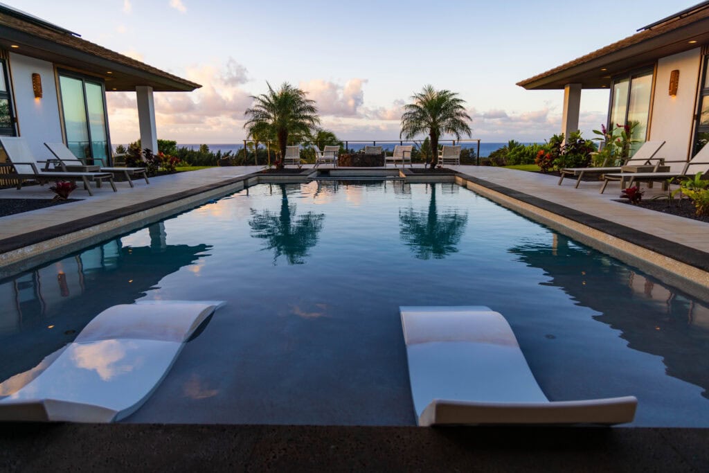 a luxury house with a pool and palm tree in kauai overlooking a golf course and ocean