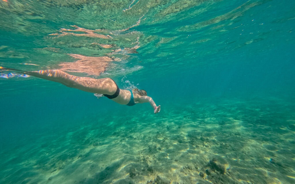 a swimmer goes under water in kauai