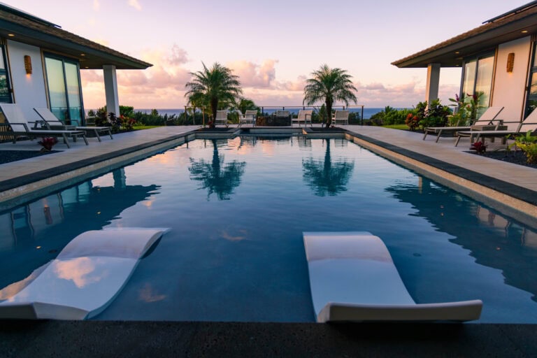 a pool at a vrbo in kauai with two palm trees in the background