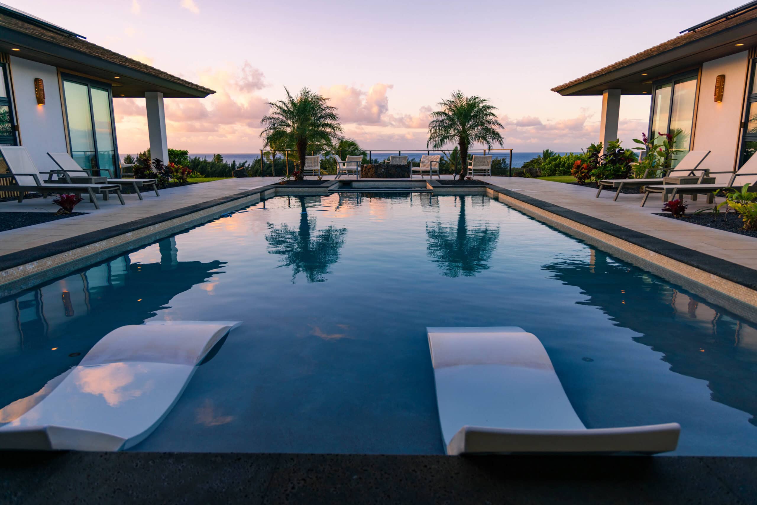 a pool at a vrbo in kauai with two palm trees in the background