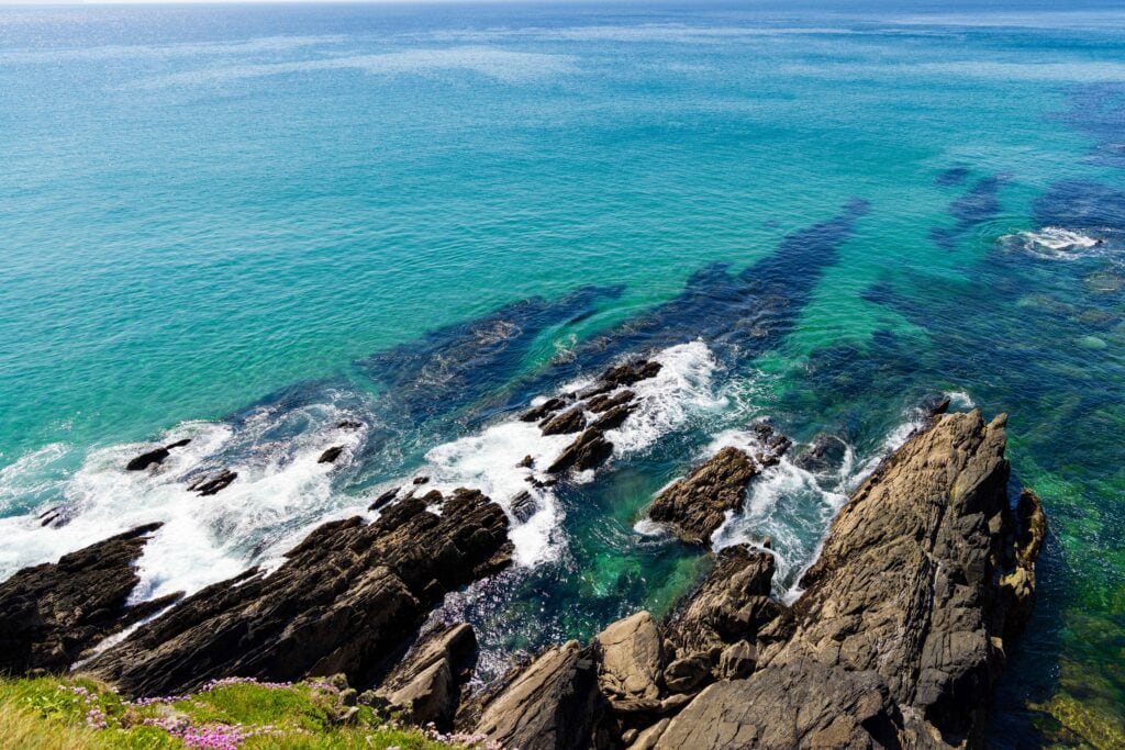 Looking down on rocky shores with light blue water.