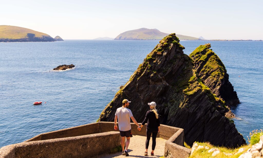a couple walks down the path near the dunquin pier in ireland