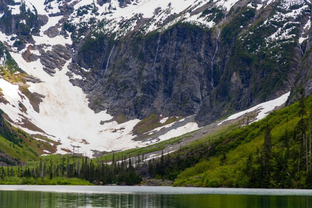 waterfalls coming down the giant rock face at goat lake in washington