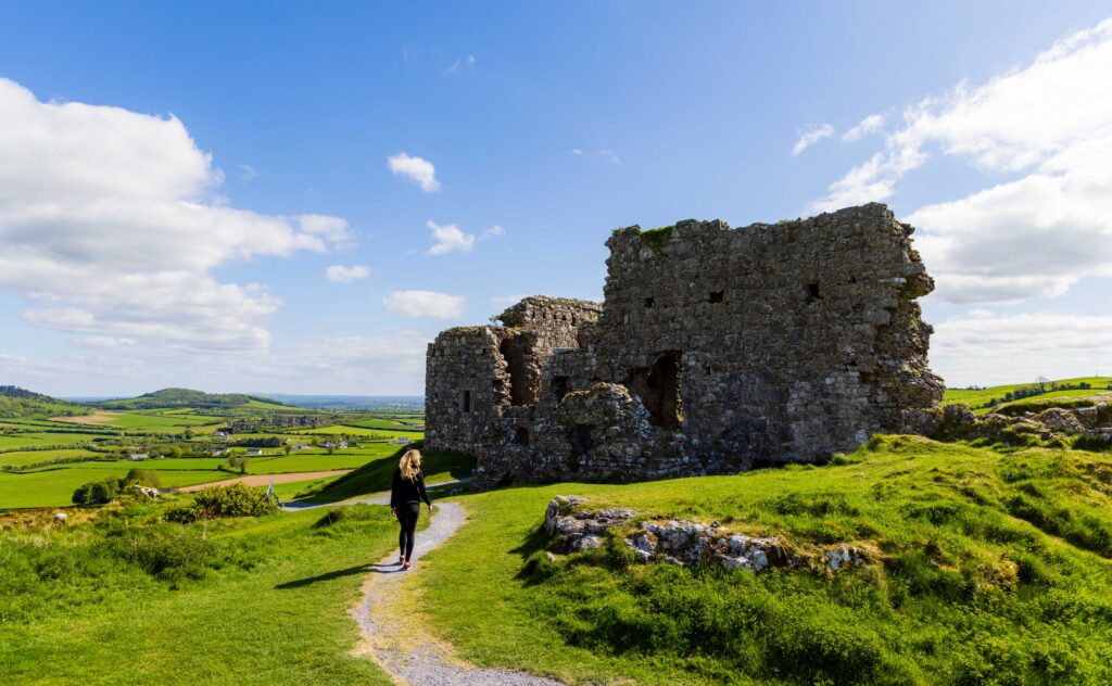 a female hiker walks near a castle in ireland 