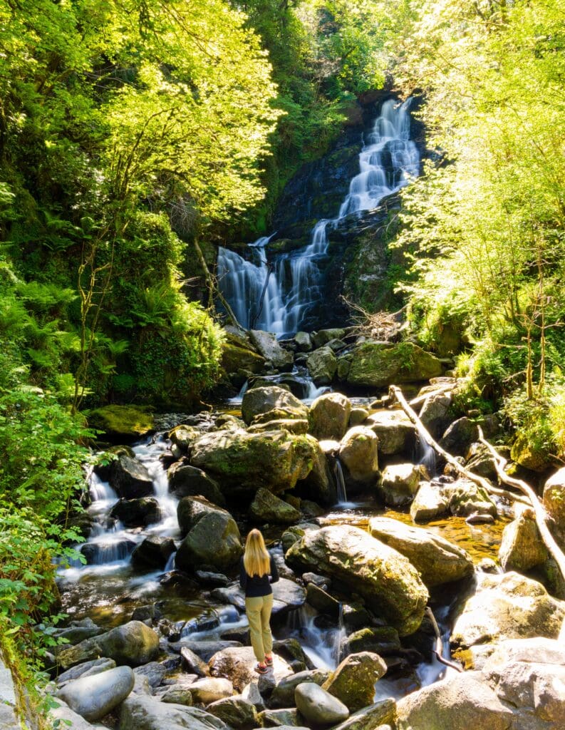 the torc waterfall cascading down with a female looking on from below