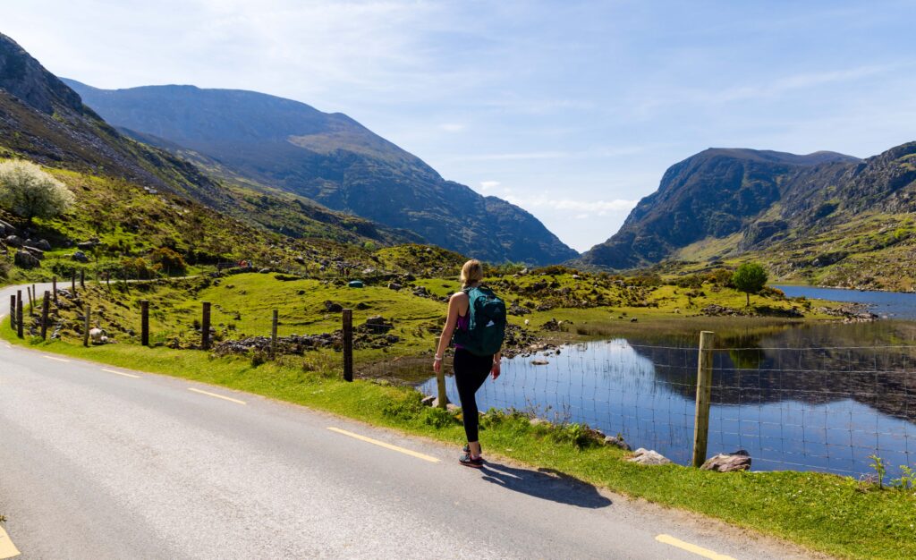 a hiker walking on the road towards the gap of dunloe in ireland