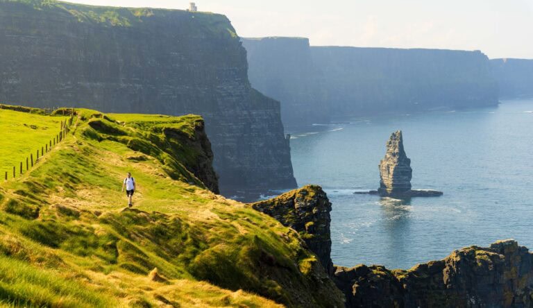 a hiker walks along the cliffs of moher in ireland