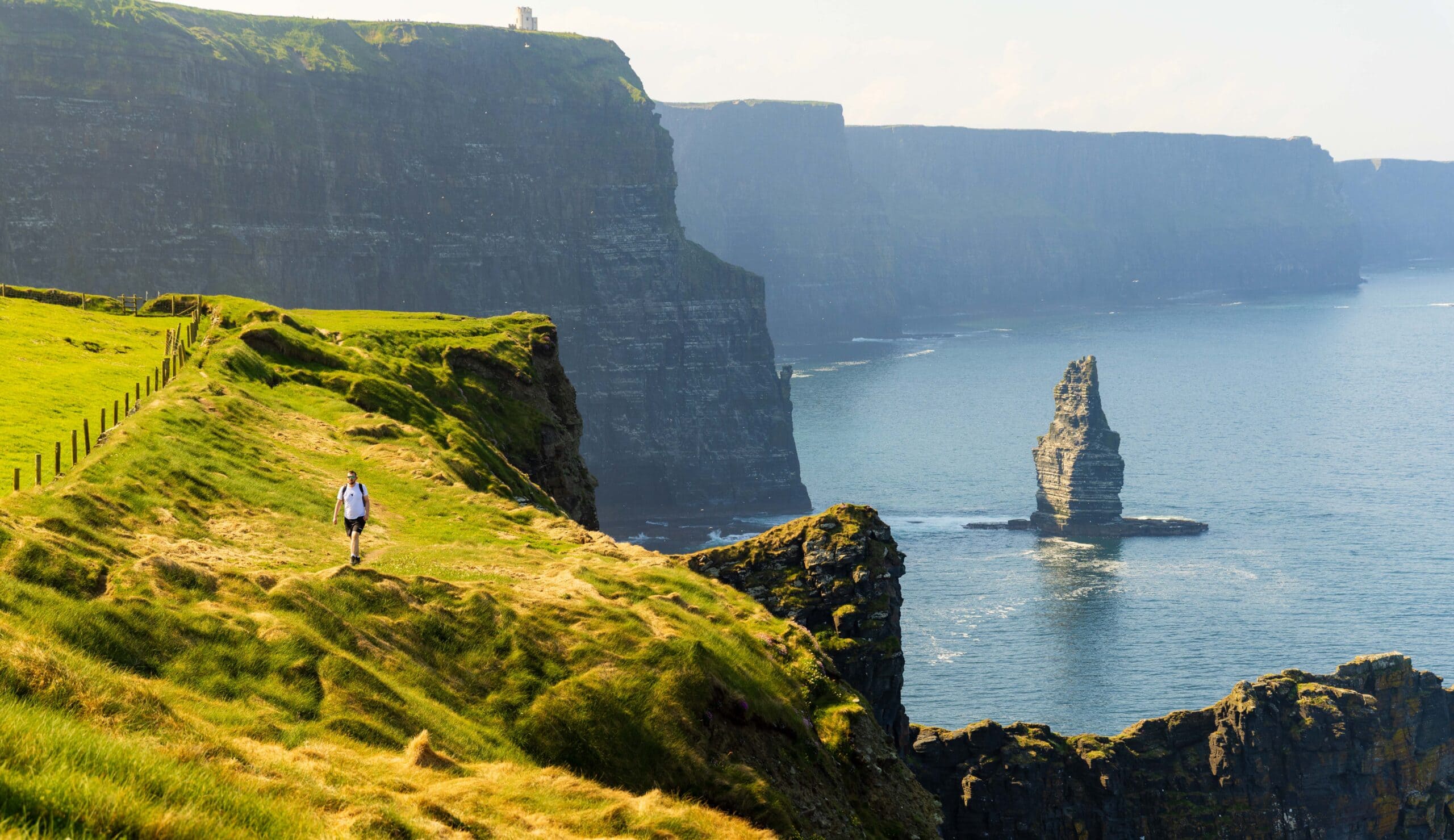 a hiker walks along the cliffs of moher in ireland