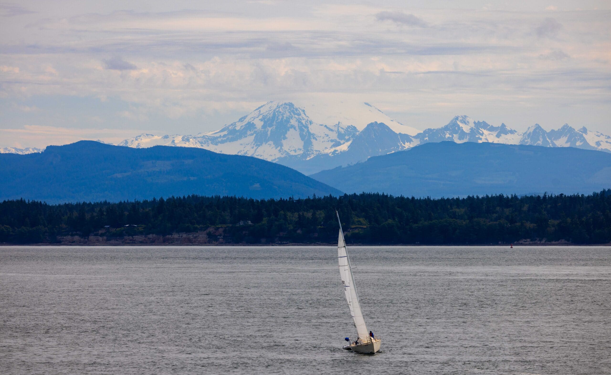 a sail boat in the san juan islands with a cloudy mount baker in the background