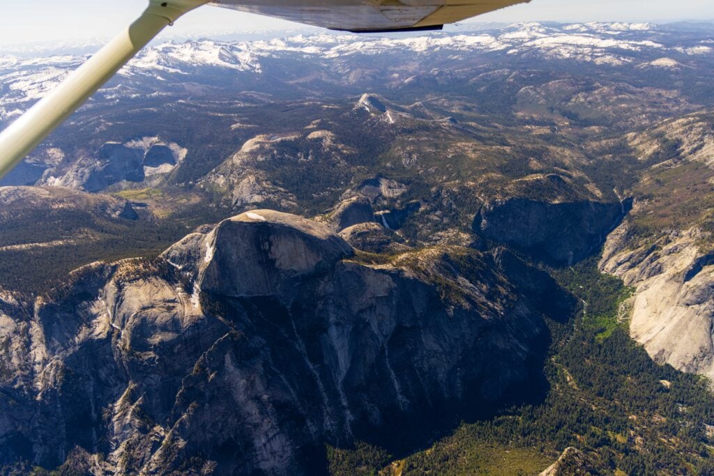 looking down on Yosemite valley with a plane wing at the top of the image. taken from a yosemite flightseeing tour