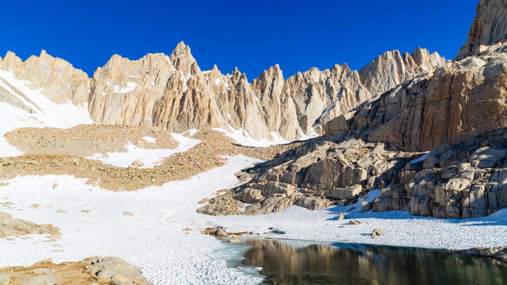a small pond below the jagged spires of mount whitney in the sierra nevada mountains