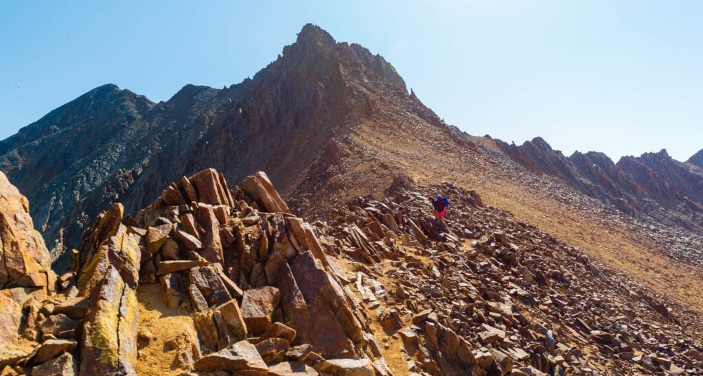 a hiker climbs on the rocky trail of mount wilson in colorado