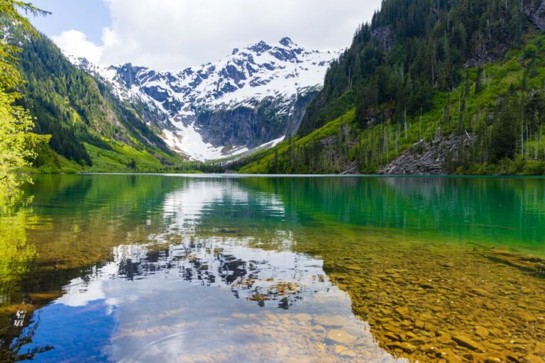 a reflection at goat lake with mountains and trees around