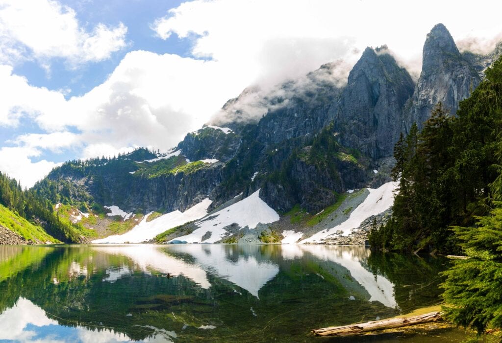 a mountain lake in Washington with reflections of snow and trees
