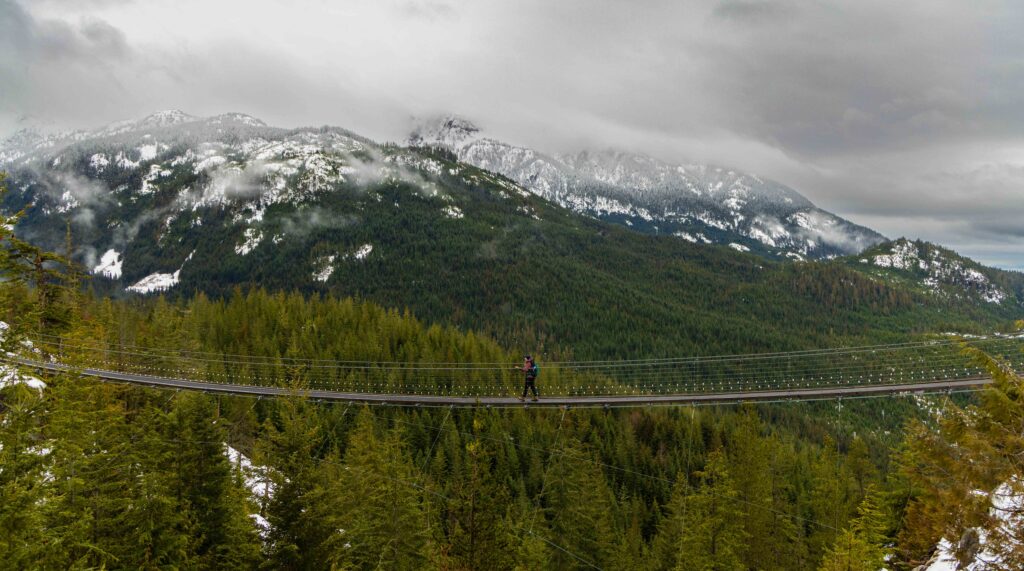 a hiker on a suspension bridge near the sea to sky gondola