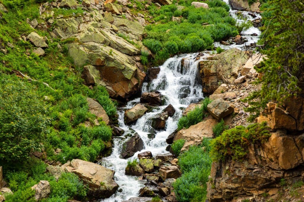 a cascading stream on the sky pond trail in rocky mountian national park. Green grass hug the shores
