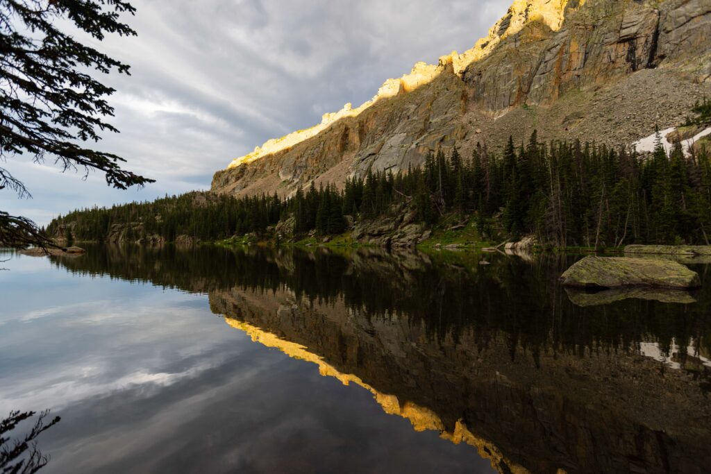 a clear reflection of rocky mountains and trees on a lake