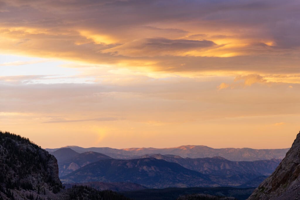 orange sunset colors in the sky over the mountains to the north of sky pond