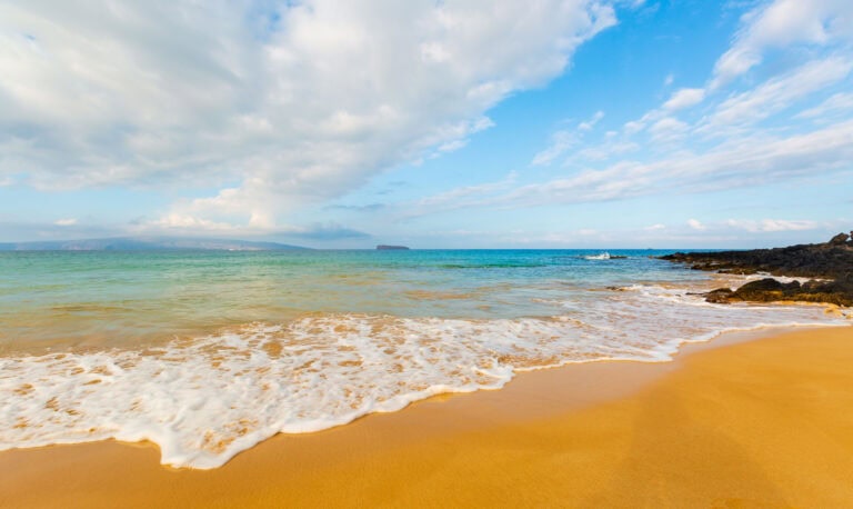 a beach on maui with blue sky and some clouds
